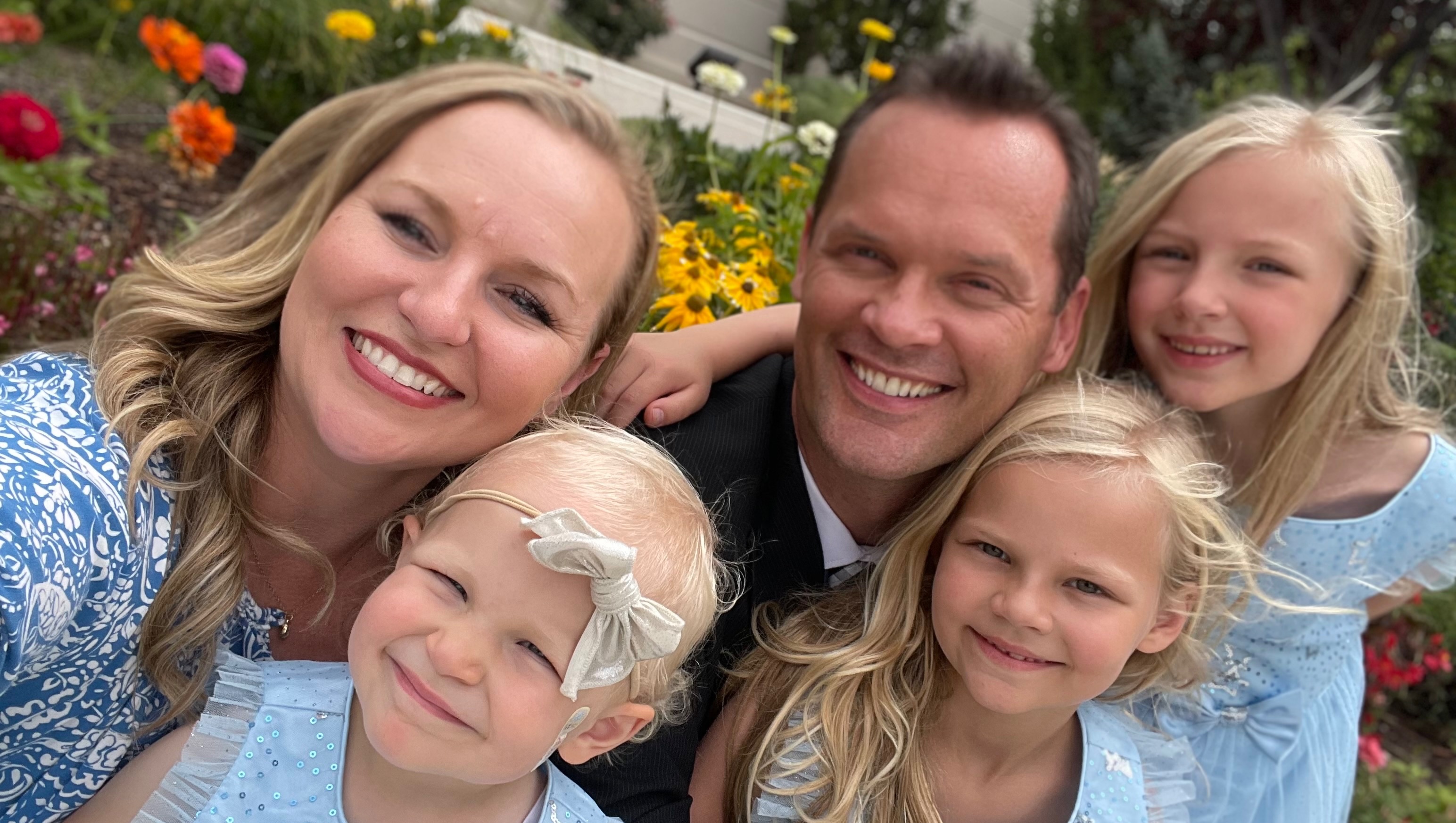 Hazel with her mom, dad, and her sisters Ivy and Ruby, in front of a garden of flowers